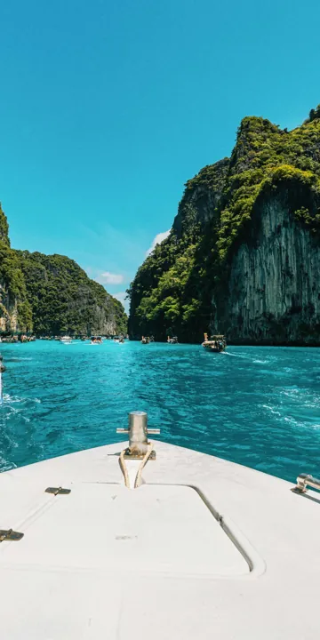 Boat bow heading into a green Thai bay